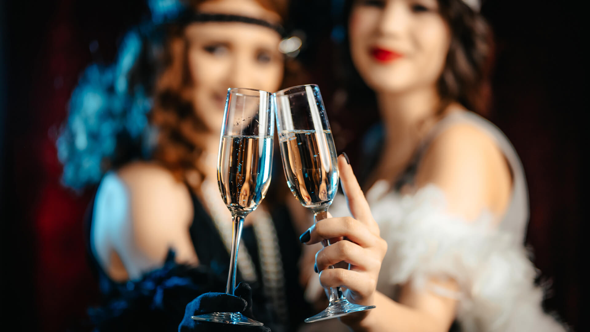 两个穿着20世纪20年代falpper裙子的女人，每人拿着一杯起泡的葡萄酒