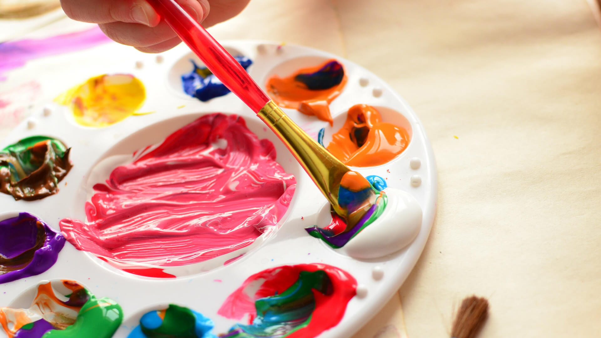 塑料画家的pallette的特写镜头，孩子将刷子浸入颜色中